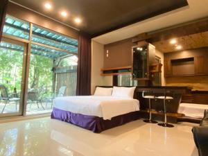 a bedroom with a bed and a kitchen with a balcony at 五柳園休閒農場-嘉義市民宿001號 in Chiayi City