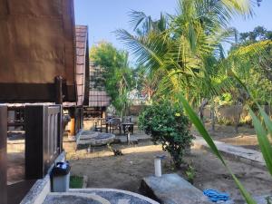 un patio con un banco y una palmera en Meno Turtle BUNGALOWS, en Gili Meno