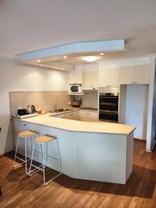 a kitchen with white cabinets and a counter with stools at Bayview Bay Apartments and Marina in Gold Coast