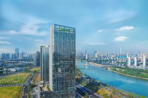 a tall building next to a river in a city at Holiday Inn Changsha Malanshan, an IHG Hotel in Changsha