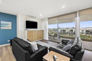 een woonkamer met 2 leren banken en een televisie bij Resort Penthouse 305 in Torquay