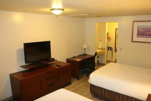 a hotel room with a bed and a flat screen tv at Empire Inn & Suites in Red Deer