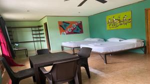 a room with two beds and a table and chairs at Be My Guest Cabinas in Puerto Viejo