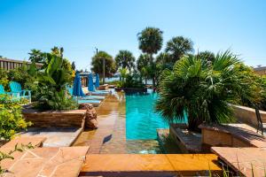 a pool at a resort with palm trees and blue chairs at Sangria Sunset in Rockport