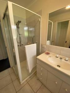 a bathroom with a shower and a sink and a mirror at Yarra House - Comfortable 3 bedroom home close to everything! in Healesville