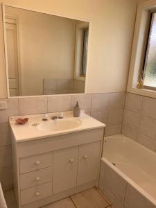 a bathroom with a sink and a mirror and a tub at Yarra House - Comfortable 3 bedroom home close to everything! in Healesville