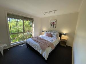 a bedroom with a bed and a large window at Yarra House - Comfortable 3 bedroom home close to everything! in Healesville