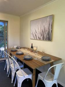a long wooden table with chairs and a bottle of wine at Yarra House - Comfortable 3 bedroom home close to everything! in Healesville