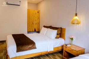 een slaapkamer met een groot wit bed en een nachtkastje bij BB Hotel&Resort in Phu Quoc