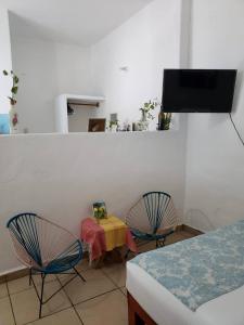 Habitación con 2 sillas, mesa y TV. en Las Palmas en Zihuatanejo