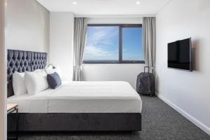 a hotel room with a bed and a window at Meriton Suites Kent Street, Sydney in Sydney