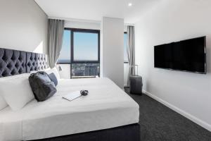 a hotel room with a bed and a television at Meriton Suites Kent Street, Sydney in Sydney
