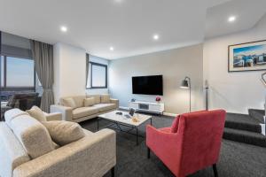 sala de estar con sofá, sillas y TV en Meriton Suites Kent Street, Sydney en Sídney