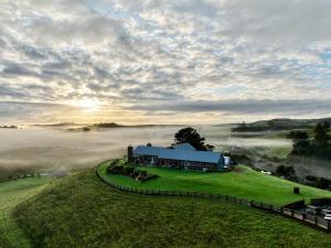 a house on a hill with fog in the field at Kauri Glen BnB in Te Arai