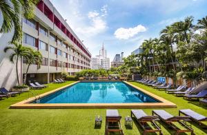 einen Pool mit Liegestühlen und ein Gebäude in der Unterkunft Ambassador Hotel Bangkok - SHA Extra Plus in Bangkok