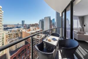 - Balcón con mesa y sillas en un edificio en Meriton Suites Kent Street, Sydney en Sídney