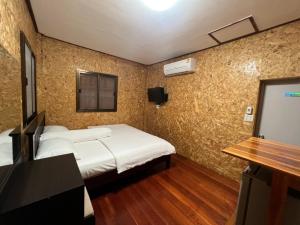 een slaapkamer met een bed en een televisie en een muur bij Nadoiview Homestay นาดอยวิวโฮมสเตย์ in Pua