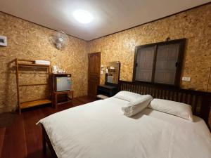 een slaapkamer met een wit bed en een televisie bij Nadoiview Homestay นาดอยวิวโฮมสเตย์ in Pua