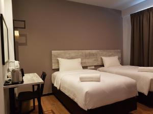 a hotel room with two beds and a table and a desk at The Leverage Lite (Kuantan) in Kuantan