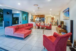 ein Wohnzimmer mit roten Sofas und ein Esszimmer in der Unterkunft Pavillions 1 - NEW Waterside Luxury with pool in Hamilton Island