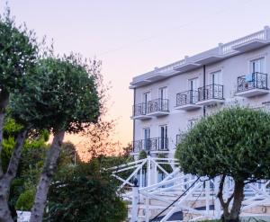 un edificio blanco con árboles delante de él en Gardenland Resort, en Shkodër