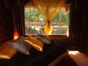 a bed with pillows and a window with a view at Casa Mango in Tulum