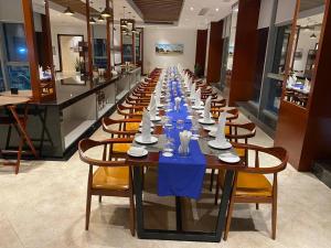 a long table in a restaurant with blue tables and chairs at V V Hotel Battambang in Battambang