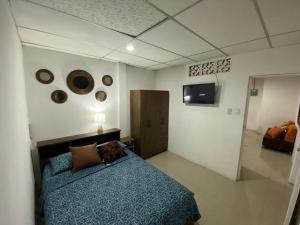 1 dormitorio con 1 cama azul y TV en SUITES AMOBLADA, en Guayaquil