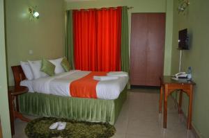 1 dormitorio con 1 cama con cortina roja en Hotel Winstar en Eldoret