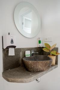 a bathroom with a stone sink and a mirror at The Moon Hostel in Batununggul