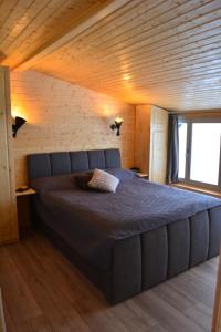 a large bed in a room with a wooden ceiling at Magura little chalet in Măgura