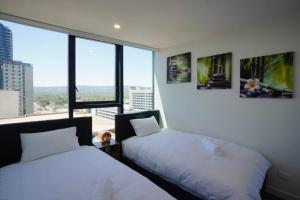 two beds in a room with a large window at City Zen Apartment-Gym-BBQ in Adelaide