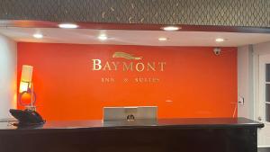 uma parede laranja com um sinal para uma pousada e suites baymont em Baymont Inn by Wyndham Odessa University Area em Odessa