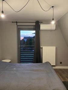 een slaapkamer met een bed en een raam met uitzicht bij Dom Villa Forest z dwupoziomowym 120 m apartamentem in Kuźnia Raciborska