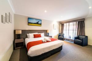 a hotel room with a bed and two chairs at Parkes International in Parkes