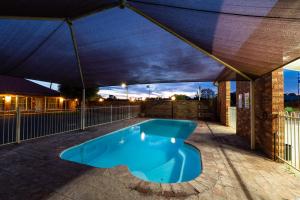 a blue swimming pool under a blue umbrella at Parkes International in Parkes