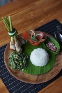 un plato de comida con arroz y verduras en una mesa en Ume Dukuh Home Sidemen, en Sidemen