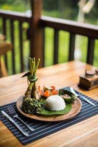 a plate of food with rice and vegetables on a table at Ume Dukuh Home Sidemen in Sidemen