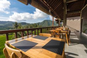 terraza con mesas de madera y sillas en el balcón en Ume Dukuh Home Sidemen en Sidemen