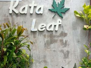 un segno per una foglia di lata su un muro con piante di Kata Leaf Resort Phuket - SHA Extra Plus a Kata Beach