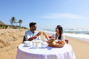 mężczyzna i kobieta siedzący przy stole na plaży w obiekcie InterContinental Chennai Mahabalipuram Resort, an IHG Hotel w mieście Mahabalipuram
