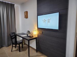 een kamer met een tafel en een televisie aan de muur bij Yu Hotel Chinatown in Kuala Lumpur