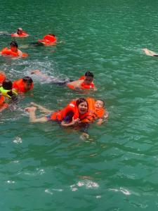 un groupe de personnes dans l'eau portant des gilets de sauvetage dans l'établissement Bee lucky homestay cat ba Island, à Xuan Dam