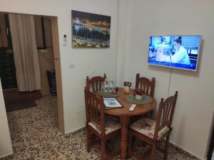 mesa con sillas y TV en la pared en Casita La Playa, en Málaga