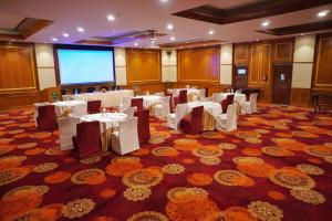 a conference room with white tables and a projection screen at Gem Park Ooty in Ooty