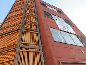 Un edificio alto y rojo con un reloj encima. en Sapporo Guest House Nariya, en Sapporo