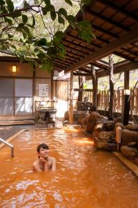 Un niño en un charco de agua en una casa en Arima Onsen Gekkoen Yugetsusanso, en Kobe