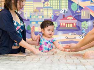 a baby sitting on the floor next to a woman at Jozankei View Hotel in Jozankei