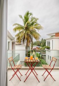 a balcony with a table and chairs and a palm tree at La Olalian Estate in Anjuna
