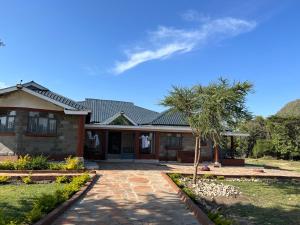 ein Haus mit einer Palme davor in der Unterkunft Masai Heritage Guesthouse in Ololaimutiek